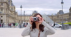 Cheerful young woman taking photos in front of the Louvre in Paris