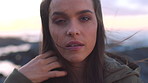 A young woman removing hair from her face on a cold, windy day at the promenade. A young woman removing her hair from her face on a windy day. A woman removing hair from her face