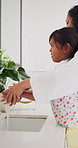 Mother teaching child washing hands in bathroom for health, hygiene and wellness at home. Bonding, learning and mom helping girl kid to clean skin to prevent germs, dirt or bacteria at house.