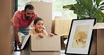 Box, moving and dad playing with child in new home for bonding, fun and quality time together. Happy, excited and young father push boy kid in cardboard at apartment, house or real estate building.