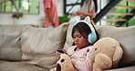 Child, phone and headphones with parents in argument, disagreement or divorce on living room sofa at home. Little girl or daughter playing on mobile smartphone with teddy bear in family conflict