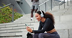 Fitness, phone and happy woman on headphones outdoor, typing in city or streaming radio by steps. Smartphone, sports and person listening to music on mobile app, video call or scroll on social media
