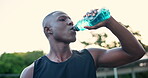 Healthy, drink and black man with bottle after sport in summer for energy and hydration. Thirsty, athlete and person on court in park drinking water on workout break with liquid in container