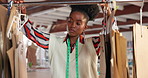 Pattern, woman and tailor at rack in workshop for choice, manufacturing or production in startup. Seamstress, fashion designer and African professional with mold on hanger, craft or creative process