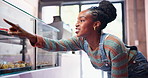 Bakery, counter and black woman with choice of pastry for happy customer in small business with treats. Cafe, sweets and girl at display window with decision for cake, dessert or cookies in glass.