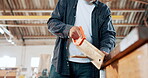 Saw, wood and carpenter in workshop with tools and construction process in garage closeup. Building, project and hands of person cutting for woodworking, manufacturing and labor in warehouse