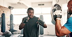 Men, boxing and personal trainer in gym for fitness, workout or training in MMA, fight and target support. Strong boxer, black people or coach helping with pads for impact, fist or exercise challenge