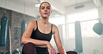 Fitness, rest and woman in gym breathing on break from workout to relax in morning with low angle. Challenge, sweat and tired girl athlete at exercise club with health, wellness and power training.