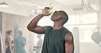 Fitness, water and man in gym with bottle on break from workout to relax at morning challenge routine. Drink, rest and sweat, tired athlete at exercise club with health and wellness at power training