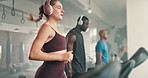Woman, fitness and running on treadmill with headphones for cardio, workout or training at gym. Female person and group of young athletes or runner on stationary machine for exercise at health club