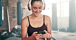 Happy woman, headphones and phone on break at gym for music, podcast or social media. Fitness, young female person or athlete in rest, relax or listening to sound on mobile smartphone at health club