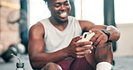 Happy, fitness and black man with phone in gym for social media, text message and online chat after workout. Sports, typing and person on smartphone or mobile app for training, exercise and wellness