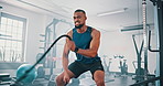 Gym, workout and black man with battle rope for muscle growth, strength development or speed exercise. Action, sports and bodybuilder resilience in functional training, fitness or endurance cardio