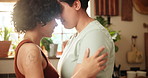 Couple, lgbtq and dancing in embrace at home, love and bonding or security in relationship. Lesbians, people and hugging on weekend in kitchen, romance and care in partnership and streaming music