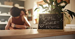 Lesbian couple, hug and blackboard sign in home for welcome, love or embrace together in kitchen. Female person, LGBTQ or gay people with chalkboard for romantic message, meeting or greeting at house