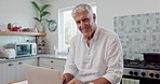 Face, laptop and senior man in home, typing and reading email on technology at table in kitchen. Portrait, smile and elderly person on computer for internet, crossword puzzle or bingo for retirement