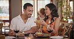 Feed, dating and couple eating in restaurant together for love, romance or anniversary celebration. Smile, fine dining or taste with man and woman sharing at romantic dinner for valentines day date