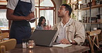 Cafe, waiter and writing customer menu order and laptop on table in restaurant for review blog on social media. Coffee shop, service and man typing with remote work and server with info on notebook