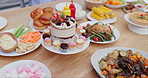 Birthday cake, table and lunch for event, celebration and party on patio with food for meal. Dessert, home and outdoor with feast, vegetable and sweet baking with cupcake and sugar snack on a plate