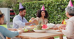 Family, eating and happy with hat at birthday party for celebration, surprise or conversation in garden of home. Couple, parents and kids with drinks for gathering and event in backyard of house