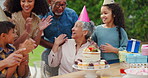 Senior woman, birthday cake and family in garden with applause, celebration and happy together for party. Man, women and children in grandparents backyard with present, dessert and love in summer