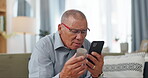 Phone, pills and senior man at home, reading label, medicine information and confused for telehealth service or FAQ. Elderly person on sofa with pharmaceutical bottle or tablet with mobile questions