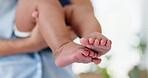 Baby, feet and parent carrying for care in home fr childhood development or love, growth or wellness. Person, infant and embrace with toes or barefoot in house or innocent youth, closeup or wellbeing