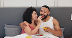 Couple in bed, breakfast and love with food, happy together with woman feeding man strawberry and orange juice. Trust, commitment and nutrition, Valentines day romance and fruit for eating with drink