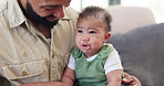 Comfort, crying and father with baby on sofa for bonding, relationship and child development in home. Family, fatherhood and dad holding sad infant child for care, support and console in living room