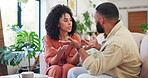 Couple, sofa and argument with fight in home with discussion, cheating or anger in living room. Man, woman and conflict with talking on couch, stress and questions with frustrated face in Colombia