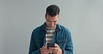 Man, happy or typing on cellphone in studio, or notification on mobile app by gray background. Designer, smile or message on smartphone on social media, connection or text for networking in mock up