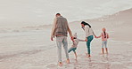 Beach, waves and parents playing children for holiday, vacation and adventure in winter. Family, travel and mother, father and kids walk in water for bonding, relationship and relax together by sea