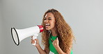 Happy woman, shouting and pointing with megaphone for motivation on a gray studio background. Excited female person screaming with bullhorn in winning, celebration or announcement for choice or pick