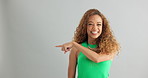 Excited woman, pointing and advertising with mockup space for marketing on a gray studio background. Portrait of happy female person with smile for notification, alert or discount deal on promotion