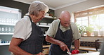 Senior couple, cooking and cutting food with knife for recipe, cuisine or ingredients in the kitchen. Serious elderly man and woman with apron for dinner preparation, meal or snack at the house