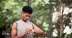 Man, fitness and running with watch for checking time, monitoring or performance at nature park. Active male person or runner looking at wristwatch to track heart rate for workout or outdoor exercise