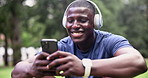 Fitness, smartphone and happy man with headphones at park on break for streaming music at garden in summer. Sports, phone or African person listening to radio, typing or laugh at meme on social media