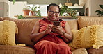 Phone, laughing and senior woman on sofa reading funny, comic or comedy online blog on website. Happy, relax and mature African female person scroll on article website with cellphone in living room.