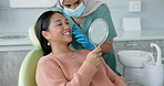 Dentist, teeth and woman with mirror for dental care, medical appointment or consultation at clinic. Healthcare, asian female patient and orthodontist for oral hygiene, wellness and cleaning.