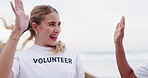 Happy woman, volunteer and beach with high five for teamwork, community service or recycling bag. Volunteering workers touching or collecting rubbish, dirt or garbage to save the earth, sea or ocean