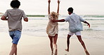 Friends, beach and running to water or excited celebration for summer vacation, adventure or holiday. Men, women and back or hands up in Florida for seaside getaway for bonding joy, fun or happiness