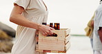 Alcohol, case and friends walking on beach for hangout on vacation, holiday or adventure. Box, hands and closeup of group of people with beer bottles by ocean or sea on weekend trip in Mexico.