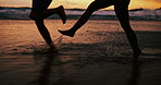 People, silhouette and legs with water splash on beach at night for fun holiday, weekend or bonding. Closeup of friends running, playing or enjoying outdoor nature in late evening on the ocean coast