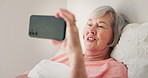 Senior woman, bed and video call with phone for conversation, communication or networking at home. Elderly female person with smile and talking on mobile smartphone for virtual discussion at house