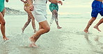 People, diversity and legs with water splash on beach for fun holiday, weekend or summer vacation. Group of diverse friends running, playing or enjoying outdoor nature on the ocean coast by the sea