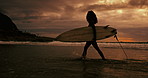 Woman, silhouette and walking with surfboard on beach at night for waves, sport or outdoor surfing in nature. Female person or surfer on ocean coast in late evening for surfing, holiday or weekend