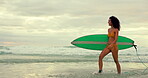 Beach, surfer in summer and woman walking with surfboard on sand by sea or ocean for travel. Smile, bikini and morning with happy young person surfing at coast for sports, training or leisure hobby