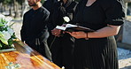 Funeral, family and woman with bible at graveyard for memorial service, burial and prayer for faith, support and comfort. Death, grief and people at cemetery with holy book, care and word at coffin.