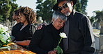 Graveyard, mature man and woman hug at funeral, memorial service or burial in empathy, support and comfort. Death, grief and people embrace at cemetery with flower, care and family together at coffin