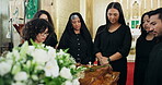 Funeral, church or family by coffin with flowers at memorial service for respect, support and comfort. Death, grief or sad people with roses, ceremony and goodbye at casket for spiritual farewell